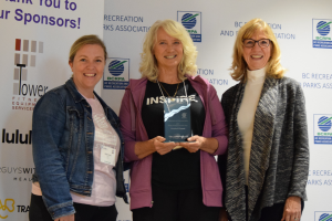 BCRAP CEO Katie Fenn on the left, next to Christina Truscott holding a glass award, and on the right is Elizabeth Ayers. All three women are smiling in front of a BCRPA backdrop.