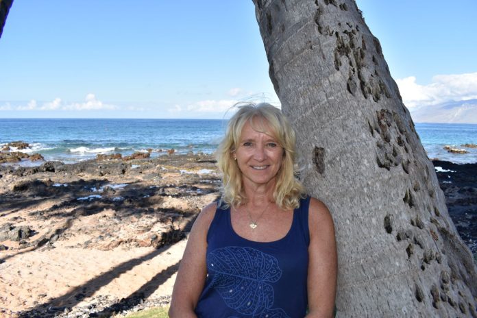 HLM Fitness Career Christina Truscott, leaning against a tree and smiling on a tropical beach.
