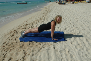 Christina Truscott in a push-up position on a sandy beach.