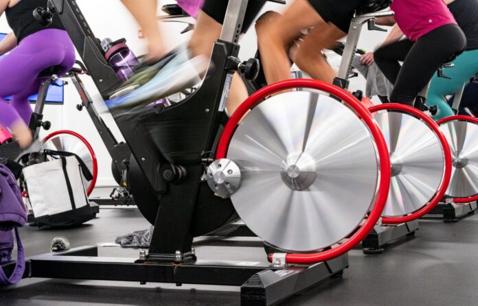 Close up of a stationary bike, showing the back wheel and blurry feet pedalling quickly.